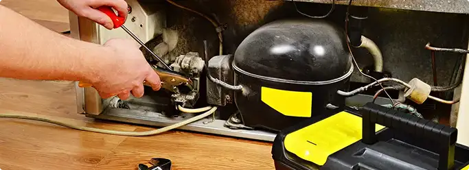 Refrigerator repair technician fixing the compressor and wiring in Hampstead, NC