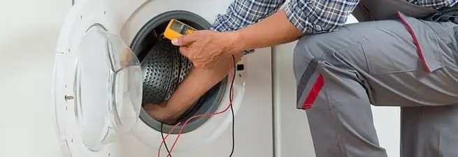 Dryer repair technician inspecting and repairing a clothes dryer in Wilmington, NC