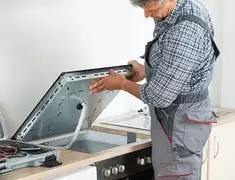Appliance repair technician installing a built-in cooktop in Wilmington, NC