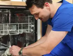Dishwasher repair technician inspecting and servicing an open dishwasher in Wilmington, NC