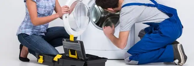 Washer repair technician inspecting a front-load washing machine with tools in Wilmington, NC