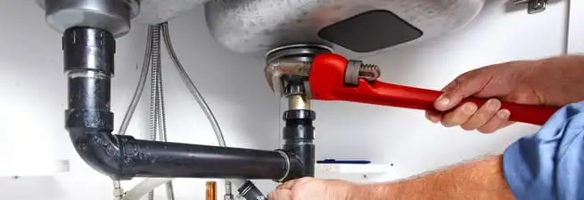Garbage disposal repair technician tightening the sink drain and disposal connection in Wilmington, NC