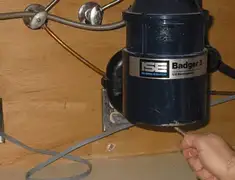 Garbage disposal repair technician tightening the mounting ring under a sink in Wilmington, NC