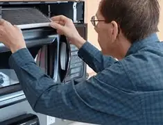 Appliance repair technician replacing a microwave vent filter in Wilmington, NC
