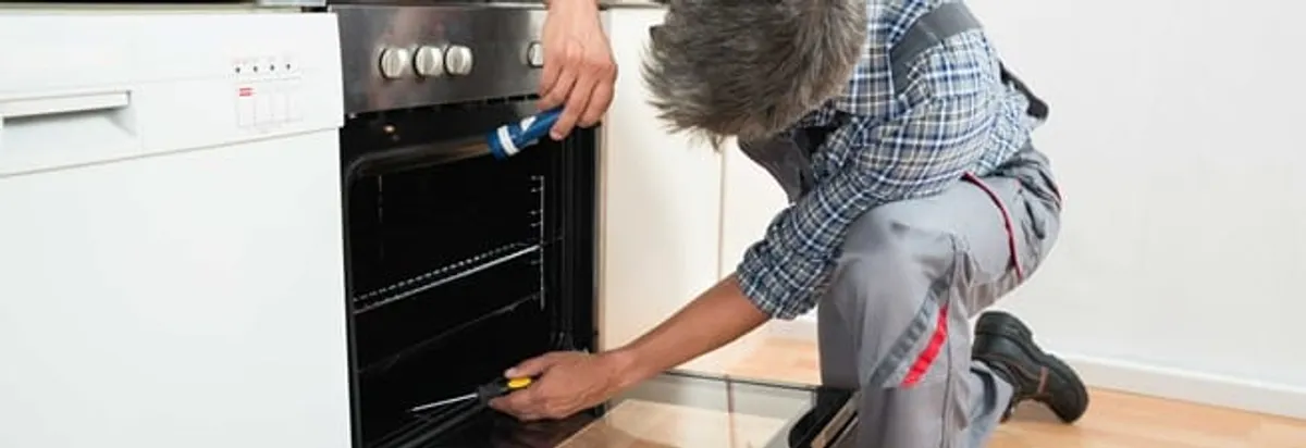 Oven repair technician inspecting and servicing an electric oven in Wilmington, NC