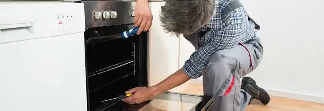Oven repair technician inspecting and servicing an electric oven in Wilmington, NC