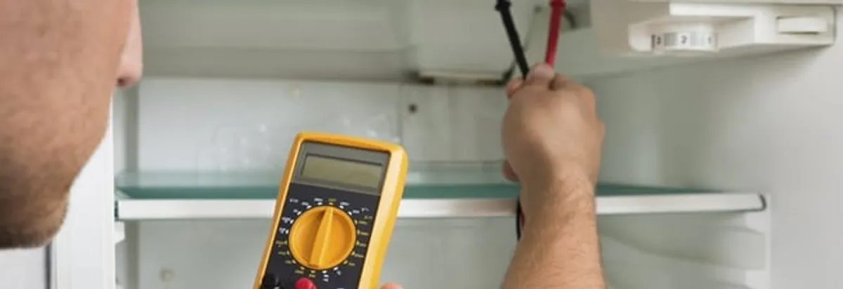 Refrigerator repair technician testing electrical components with a multimeter in Wilmington, NC