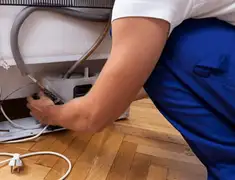 Appliance repair technician fixing refrigerator water line and connections in Wilmington, NC
