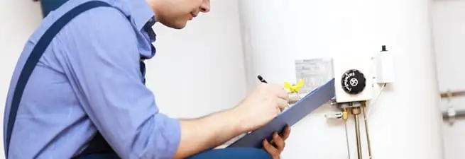 Water heater repair technician inspecting the unit and recording service notes in Wilmington, NC