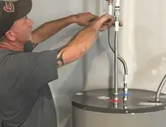 Water heater repair technician tightening supply line connections in Wilmington, NC
